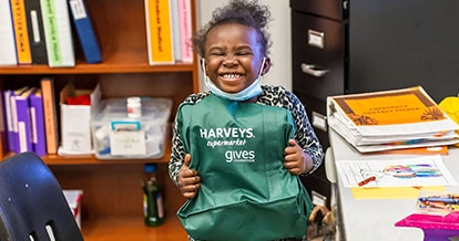 Girl happily holding a Haveys Supermaket gives foundation bag